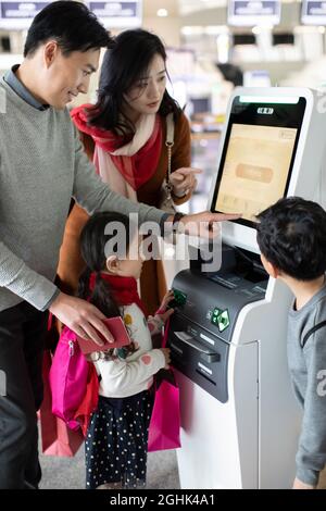 Eine glückliche junge Familie, die am Flughafen selbst einchecken kann Stockfoto