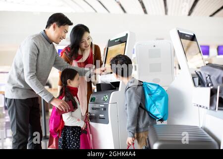 Eine glückliche junge Familie, die am Flughafen selbst einchecken kann Stockfoto