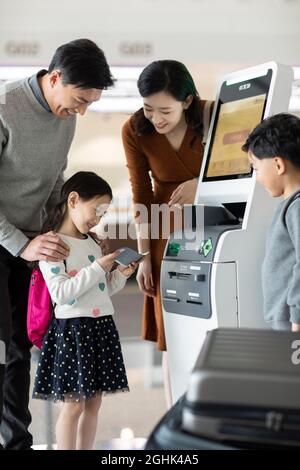 Eine glückliche junge Familie, die am Flughafen selbst einchecken kann Stockfoto