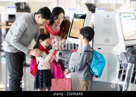 Eine glückliche junge Familie, die am Flughafen selbst einchecken kann Stockfoto