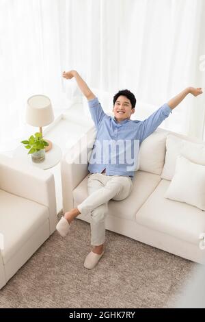 Fröhlichen jungen Mann auf sofa Stockfoto