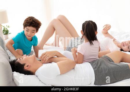 Glückliche junge Familie, die Spaß auf dem Bett hatte Stockfoto