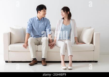 Fröhlicher junger Paare sitzen auf einem Sofa Stockfoto