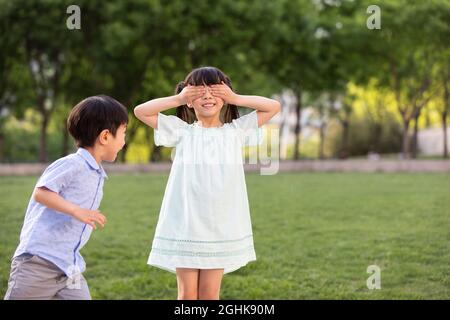 Zwei Kinder, die spielen, verstecken sich im Park Stockfoto
