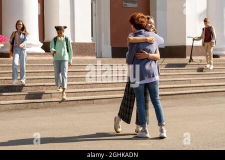 Glückliche und liebevolle Mutter und Tochter umarmen am Morgen durch das Schulgebäude Stockfoto