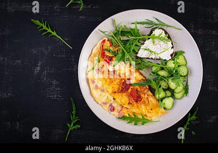 Frühstück. Omelette mit Tomaten, Käse und Salat auf weißem Teller. Frittata: italienisches Omelett. Draufsicht, flach liegend Stockfoto