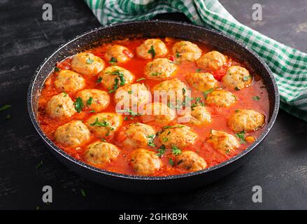 Fleischbällchen in Tomatensauce in einer Pfanne auf dunklem Hintergrund. Stockfoto