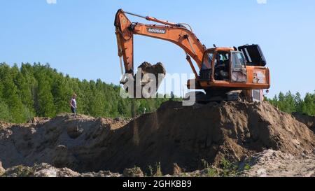 Yellow Excavator Führt Aushub Von Sandgraben Auf Der Baustelle: Moskau, Russland - 30. August 2021. Stockfoto