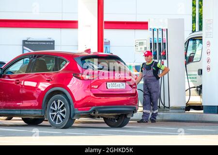 Woronesch. Russland. 23. Juli 2021. Eine man-Tankstelle in Uniform treibt einen großen roten Crossover an einer Tankstelle an. Stockfoto