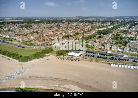 Luftaufnahme des Goring by Sea Strandes mit dem beliebten Cafe mit Blick auf den grünen Strand hinter dem Strand in diesem beliebten Badeort. Stockfoto