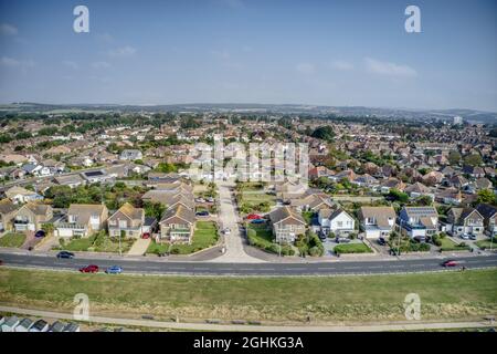 Goring by Sea breiter Strand, gesäumt von Strandhütten mit Meereshalbmond an der Seite in diesem beliebten Badeort. Stockfoto