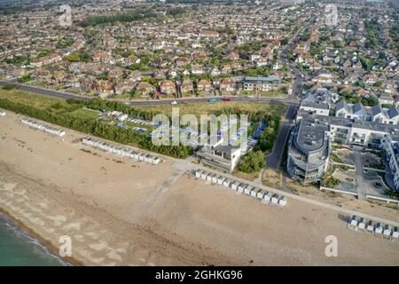 Luftaufnahme des Strandes von Goring by Sea, gesäumt von Strandhütten vor dem Yacht Club und Segeljollen. Stockfoto