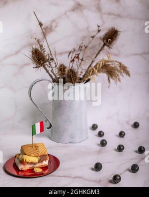 Eiscreme gefüllt Cookies mit über einer Flagge von Italien und im Hintergrund eine Vase mit getrockneten Blumen und Heidelbeeren Stockfoto