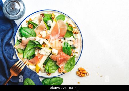 Birnensalat mit Prosciutto, Blauschimmelkäse, Spinat, Walnüssen auf weißem Hintergrund, Draufsicht, Kopierraum Stockfoto