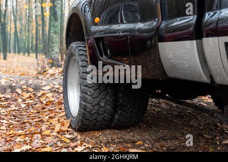 Nahaufnahme Detail unten pov Ansicht von Dual Twin Offroad Performance Rad von Super Heavy Duty Pickup LKW-Auto in Herbst Wald Landschaft Auffahrt Stockfoto