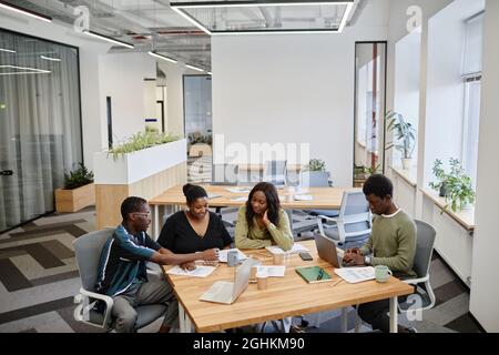 Geschäftsmann präsentiert seine kreative Idee den Kollegen bei der Besprechung und zeigt Dokumente mit Marketingdaten Stockfoto