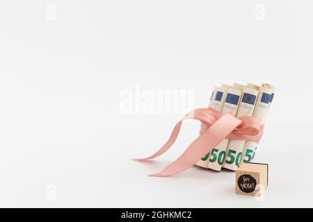 50 Euro in Rollen gebunden mit rosa Band und Würfel mit Worten für Sie darauf. Stockfoto