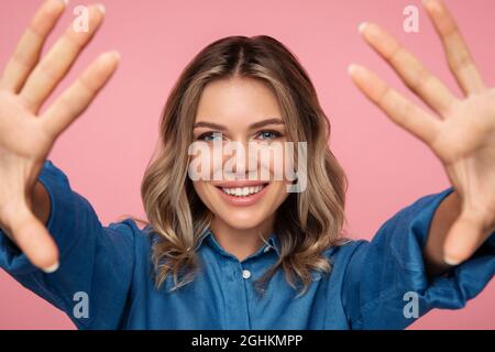 Junge blonde Mädchen halten ausgestreckte Hände, Arme offen für Umarmung in einladender Geste, um neue Klientin zu treffen Stockfoto