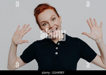 Nahaufnahme Studio-Porträt einer jungen amüsanten Rotschopf-Frau, die Handflächen hebt und etwas Lustiges sieht Stockfoto