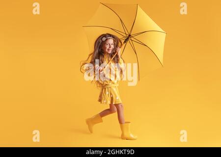 Glücklich emotionale Mädchen lachen mit Regenschirm auf farbigem gelben Hintergrund. Herbst, Frühjahrssaison. Stockfoto