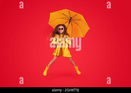 Glücklich emotionale Mädchen lachen mit Regenschirm auf rotem Hintergrund. Herbst, Frühjahrssaison. Stockfoto