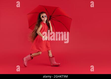 Glücklich emotionale Mädchen lachen mit Regenschirm auf rotem Hintergrund. Herbst, Frühjahrssaison. Stockfoto