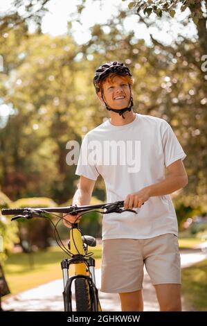 Glücklicher Mann mit dem Fahrrad auf dem Spaziergang im Park Stockfoto