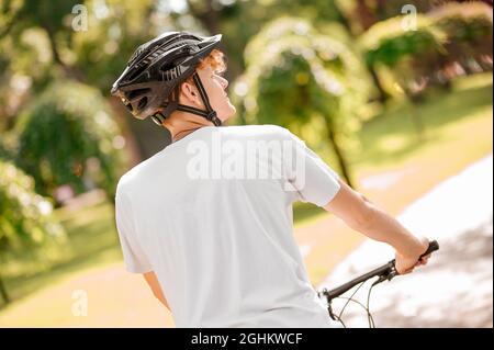 Rückansicht des Mannes im Helm auf dem Fahrrad Stockfoto