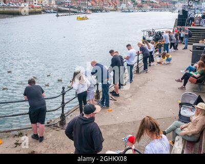 Urlauber, die im Spätsommer an der Brücke in Whitby Harbor North Yorkshire England nach Krabben fischen Stockfoto