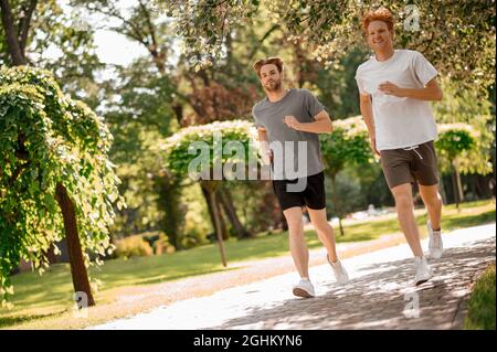 Fröhliche, energische Jungs, die im grünen Park laufen Stockfoto