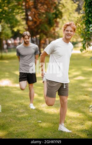 Zwei Jungs in Sportbekleidung wärmen sich auf dem Rasen auf Stockfoto