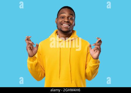 Afrikanischer Mann Mit Gekreuzten Daumen Lächelnd Zu Kamera, Blauer Hintergrund Stockfoto