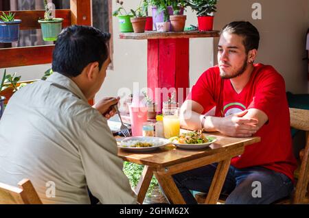 Gut aussehende junge Menschen zur Festsetzung der Tabelle mit Servietten, bevor die Gäste kommen Stockfoto