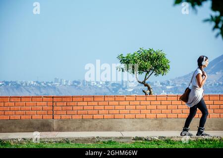 Junge Frau auf Rollschullaufbahn, die draußen in der Stadt Musik hört Stockfoto