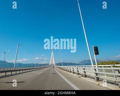 Fahren der Rion-Antirion Brücke auf der Autobahn in Patras Stadt, Griechenland. Hängebrücke über den Golf von Korinth. Die zweitlängste Brücke mit Kabelgestabeung. Sunn Stockfoto