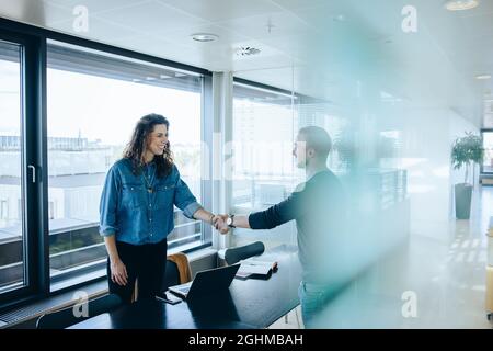 Der Arbeitgeber schüttelt nach erfolgreichem Vorstellungsgespräch Hand mit dem Mann. Geschäftsfrau gratuliert und schüttelt Hand mit Bewerberin in der Vorstandssitzung. Stockfoto