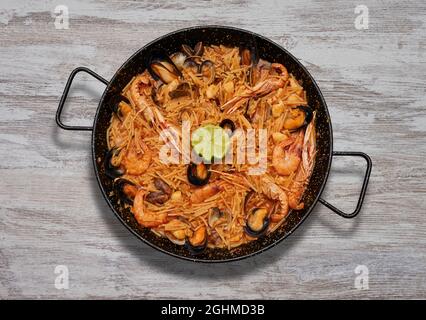 Blick von oben auf das köstliche Fidua mit Meeresfrüchten in der Pfanne auf der Holzoberfläche Stockfoto