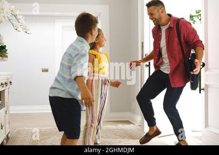 Glücklicher kaukasischer Vater, der mit seiner Tochter und seinem Sohn lächelnd nach Hause kam und ihn vor der Tür begrüßte Stockfoto