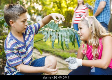 Kaukasischer Sohn und Tochter arbeiten im Garten mit Mutter und Vater im Hintergrund Stockfoto