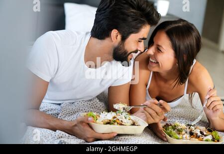 Gesundes Frühstück im Bett. Junge schöne Paar in der Liebe sitzt auf dem Bett und mit Frühstück. Stockfoto