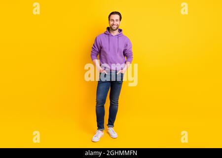 In voller Länge Foto von jungen Mann glücklich positive Lächeln Hände in der Tasche zuversichtlich isoliert über gelben Hintergrund Stockfoto