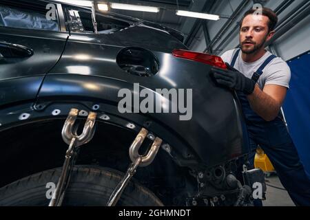 Schrauben Sie die Klemmen fest, um die Karosserie zu glätten, während der Techniker die Schlussleuchte anpasst Stockfoto