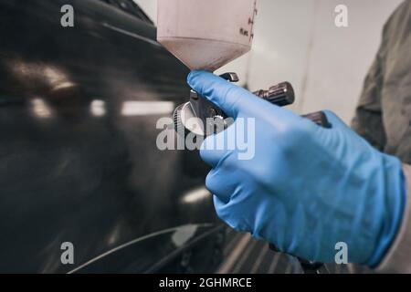 Autotechniker, der die Spritzpistole in der Nähe des Fahrzeugs hält Stockfoto