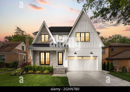 Ein neues, weißes, modernes Bauernhaus mit Felswänden bei Sonnenuntergang. Stockfoto