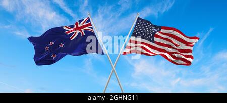 Flaggen der USA und Neuseelands winken im Wind auf Fahnenmasten gegen den Himmel mit Wolken am sonnigen Tag. Symbolisieren Beziehung, Dialog zwischen zwei Co Stockfoto