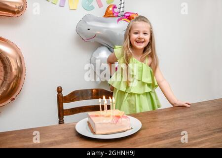 Ein Mädchen und ein Kuchen mit fünf Kerzen zu ihrem Geburtstag Stockfoto