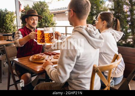 Eine Gruppe von Freunden trifft sich in der Bar, im Café und trinkt Bier beim Bierfest. Traditionen, Spaß, Freude, Freundschaft, Urlaub. Oktoberfest, oktober, Herbst Stockfoto