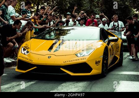 Yellow Lamborghini auf einer Straße, umgeben von einer fröhlichen Menge von Fotografen und Menschen Stockfoto