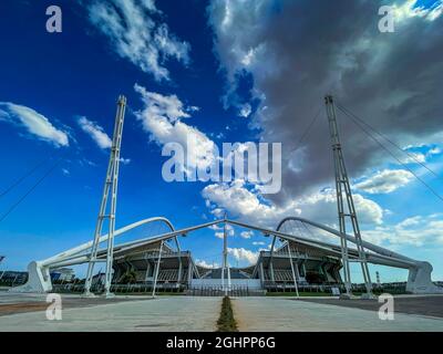 Ikonische Ansicht des Olympiastadions OAKA in Athen, Griechenland, entworfen von Santiago Calatrava mit wunderschönen Wolken und blauem Himmel Stockfoto