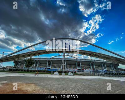 Ikonische Ansicht des Olympiastadions OAKA in Athen, Griechenland, entworfen von Santiago Calatrava mit wunderschönen Wolken und blauem Himmel Stockfoto